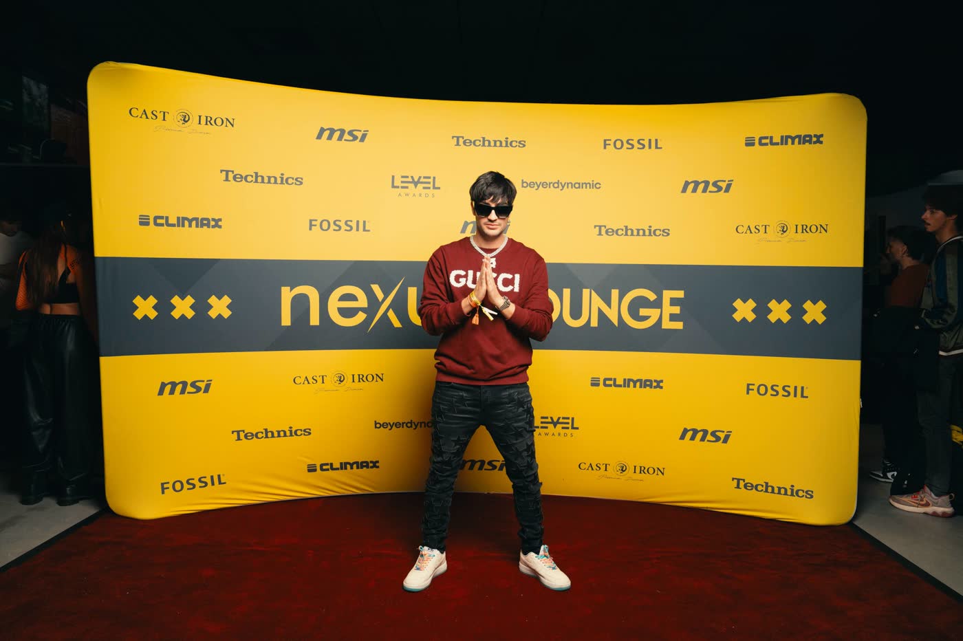 Thomas Deil on the red carpet in front of the yellow Nexus Lounge sponsor wall