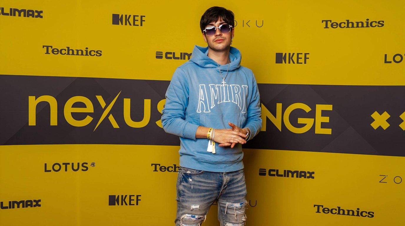 Thomas Deil standing on the red carpet against the yellow Nexus Lounge sponsor wall with Lotus, KEF, Technics and Climax logos