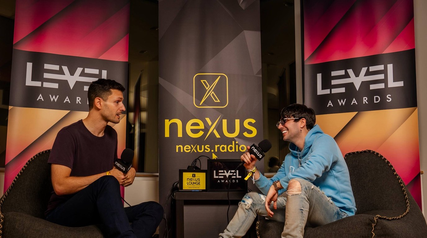 Two people mid-conversation on beanbags with Nexus Radio microphones and LEVEL Awards banners behind them at the Nexus Lounge