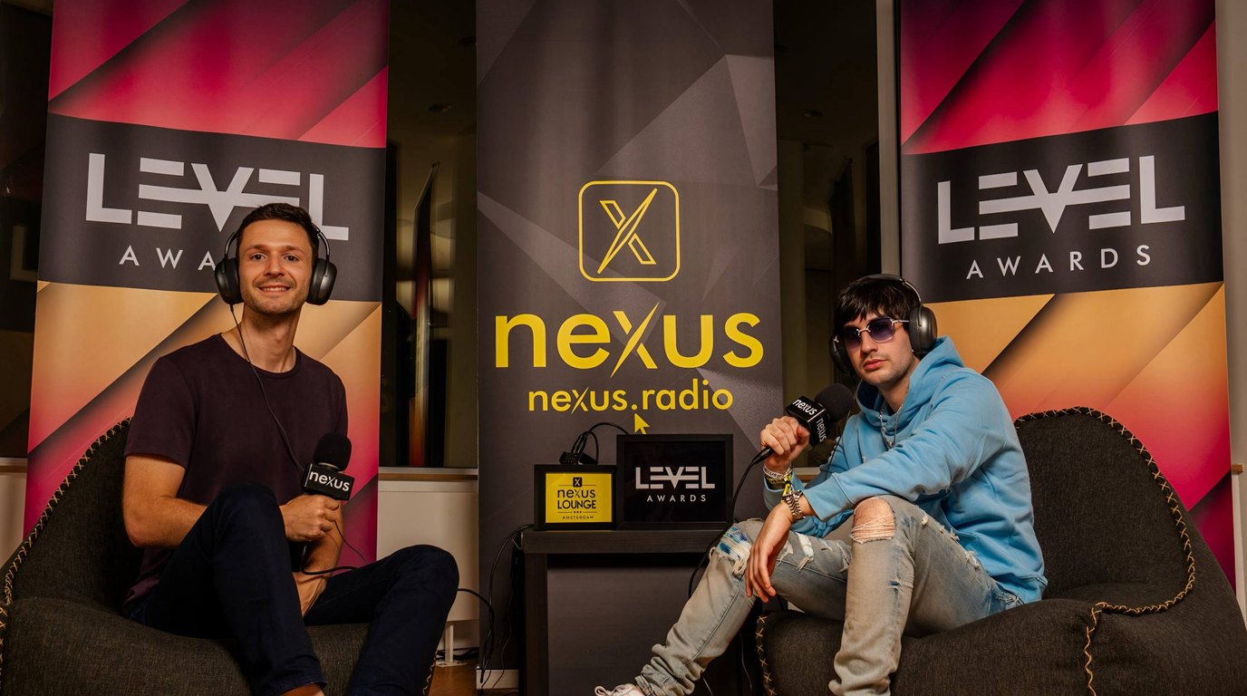 Two people seated on beanbags with Nexus Radio microphones between LEVEL Awards banners at the Nexus Lounge during Amsterdam Dance Event